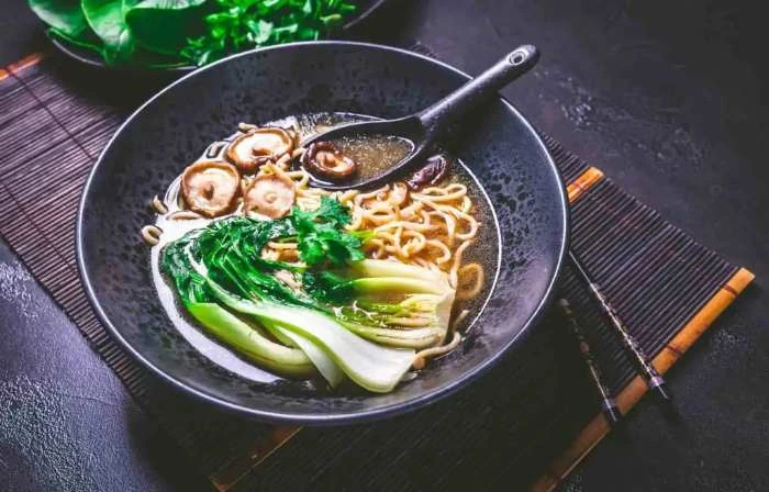 Zuppa di ramen vegana ricca di sapori umami con noodles ramen, funghi shiitake e pak choi al vapore