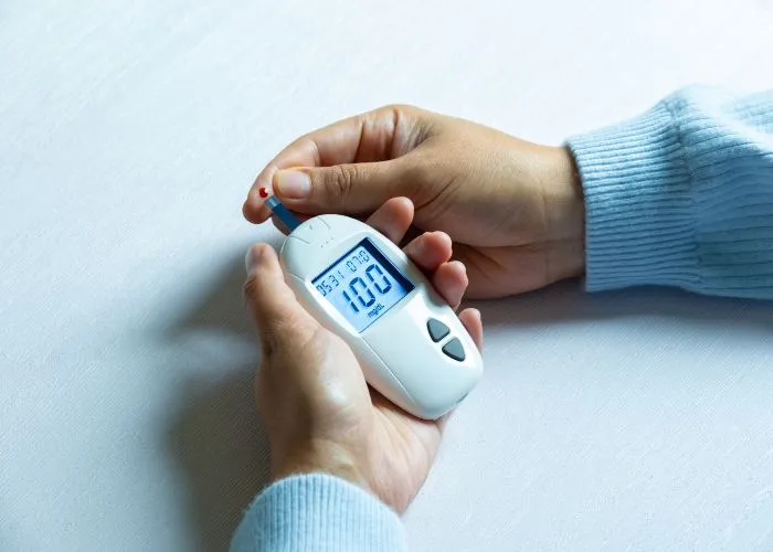 Mani di donna che controllano diabete e iperglicemia con un misuratore digitale di glicemia.
