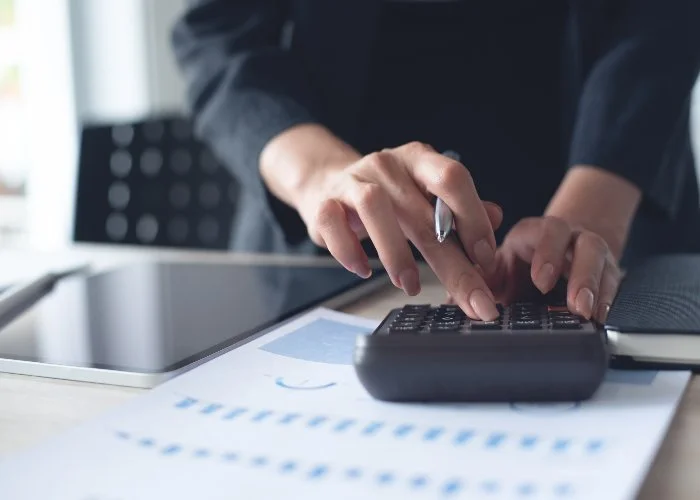 Una donna in ufficio fa dei conti con la calcolatrice