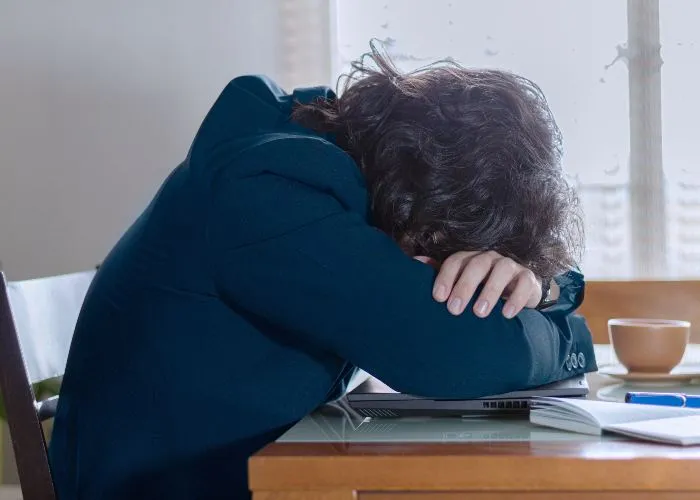 Una ragazza triste poggia il volto sopra il proprio computer