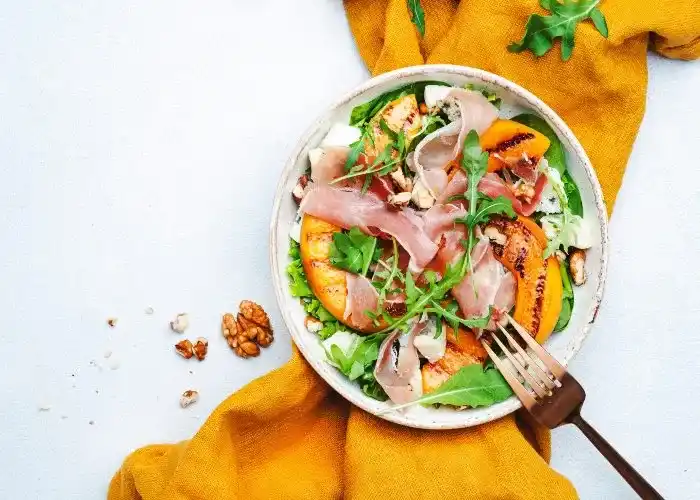 Insalata di rucola, pesche, prosciutto crudo e noci