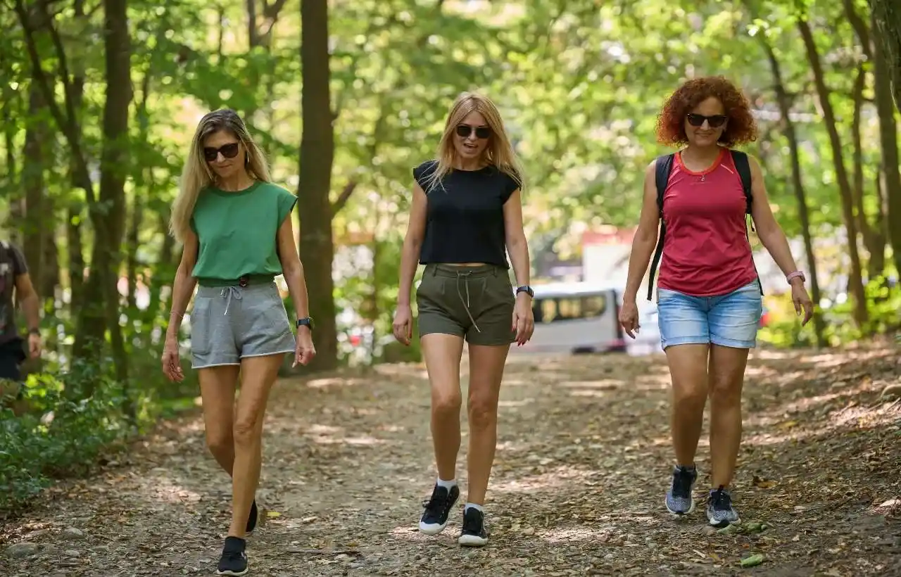Coolcation tre donne camminano al fresco in un bosco