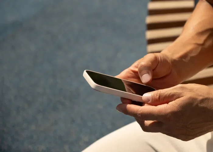 Un uomo usa lo smartphone sotto al sole