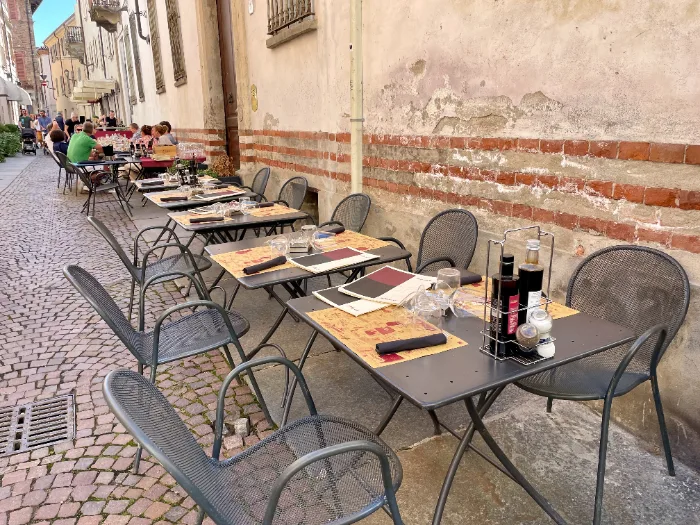 Via del centro storico di Alba con tavoli di un ristorante all'aperto