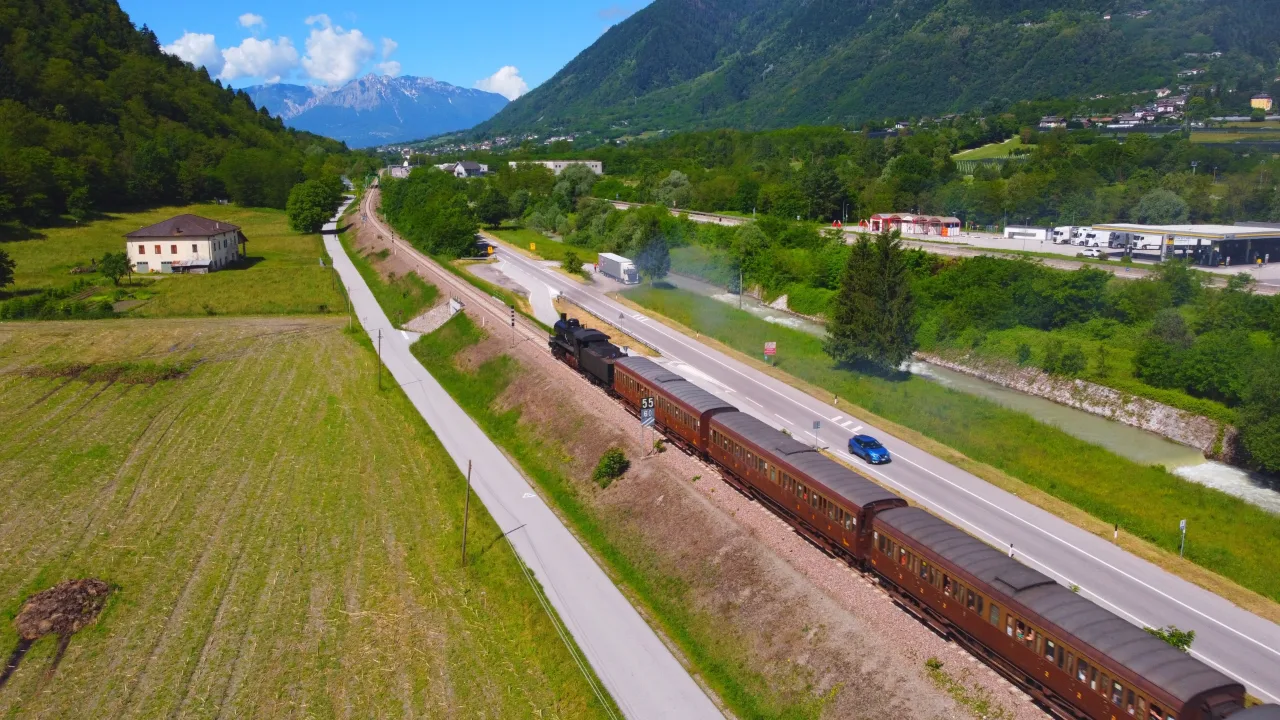 Treno storico con carrozze d'epoca in un paesaggio alpino, come il treno dei mercatini di Natale in Alto Adige