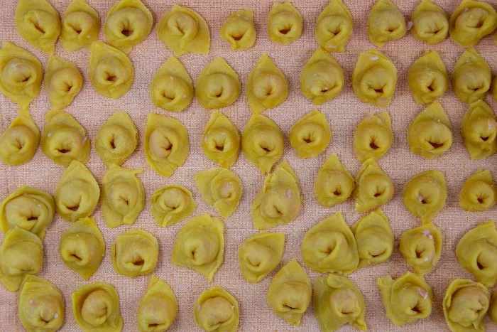 Tortellini freschi appena fatti, ripieni di carne, disposti su un piano